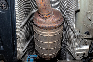 A diesel particulate filter in the exhaust system in a car on a lift in a car workshop, seen from...