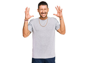 Handsome man with tattoos wearing 90s style celebrating mad and crazy for success with arms raised...