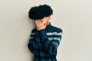 Young african american man with afro hair wearing casual clothes with sad expression covering face with hands while crying. depression concept.