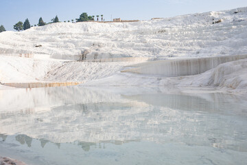 Smooth mirror reflective surface of water in thermal bath travertine terrace Pamukkale mountain in Turkey.