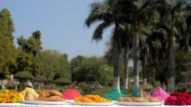 Beautifully decorated table for Holi festival celebration. Pan shot of multicolor Gulal and traditional sweets on the occasion of the Indian festival of colors - Holi