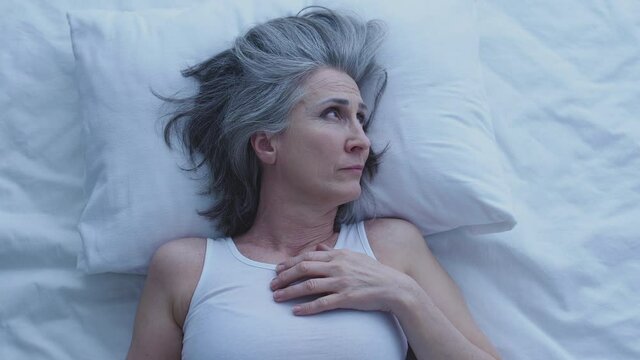 Sad unhappy woman lying in bed, suffering insomnia and loneliness, depression