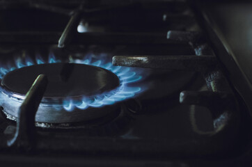 Burning blue gas on the stove. Focus on the front edge of the gas burners. Close-up.