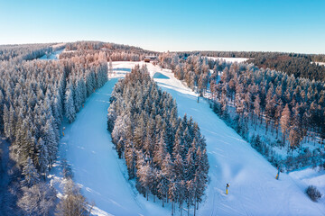 Air view on the winter sports slopes at the ski lift carousel Winterberg. Sledding slope and ski slopes between snow covered spruce forests. - obrazy, fototapety, plakaty