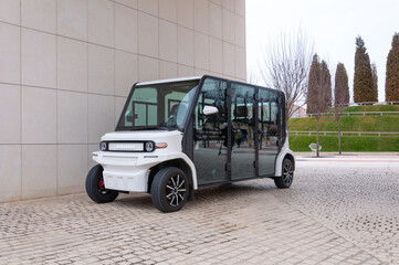 Electric street vehicle with zero emission stands near the wall in the park. The road is paved with...