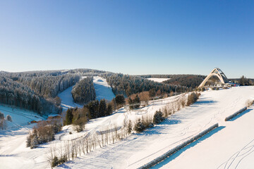 The Saint George ski jump and the ski slopes from the ski lift Carousel Winterberg photographed from the air. In the beautiful winter weather the winter sports area is deserted.