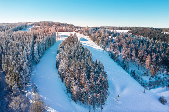 Air view on the winter sports slopes at the ski lift carousel Winterberg. Sledding slope and ski slopes between snow covered spruce forests.