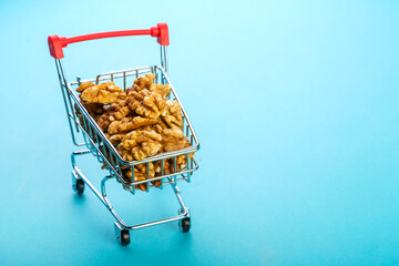 Food cart filled with peeled walnuts on a blue background. Copy space.