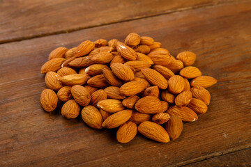 Almond nuts are sprinkled on a dark wooden table.