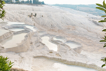 Smooth ascent to travertine mountain Pamukkale with bowls of water baths, at tourist resort in Turkey.