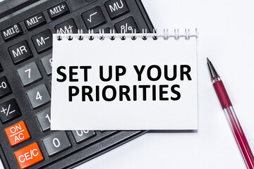 Text SET UP YOUR PRIORITIES on NOTEBOOK , CALCULATOR on white background.