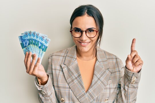 Young brunette woman holding hong kong 20 dollars banknotes smiling happy pointing with hand and finger to the side