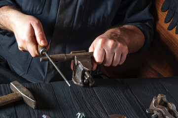 The master grinds the part with a file in a vice. Working environment in the workshop