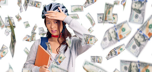 Young beautiful chinese girl wearing student backpack and bike helmet holding book stressed and...