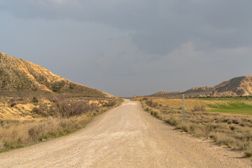 gravel road leading into a wild desert landscape under an expressive cloudy sky