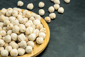 White chickpeas scattered on a black stone background.