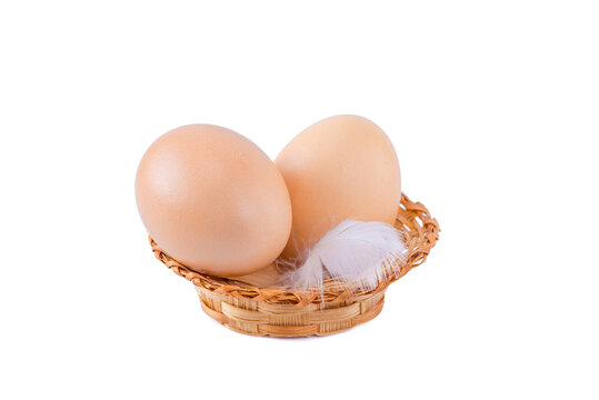 Two eggs in a small basket with a feather, isolated on a white background.