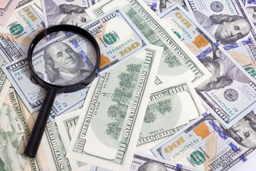 Magnifying glass on the background of bundle dollars - texture, background
