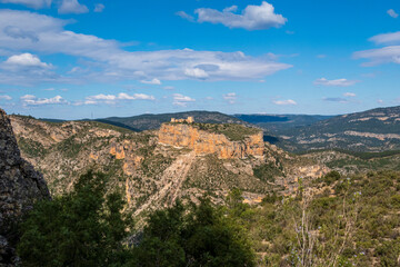 Fototapeta na wymiar Natural environment of Cortes de pallás, in Valencia (Spain), with views of its mountains, Chirel Castle and its coniferous forests. On a sunny and cloudy day.