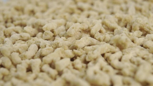 Texturized soy granules fall into a pile in slow motion. Macro. Vegetarian meat analog. Dolly shot
