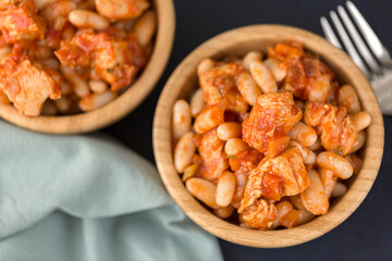 Pork stew with white beans in a wooden bowl.
