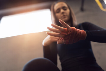 Woman is wrapping hands with red boxing wraps