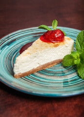 Slice of fresh delicious cheesecake with strawberry and leaf of mint