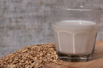 pile of raw oatmeal near a glass of milk. healthy breakfast. vegan oat milk.