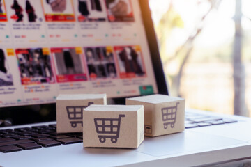 Online shopping. Cardboard box with a shopping cart logo on laptop keyboard. Shopping service on The online web. offers home delivery