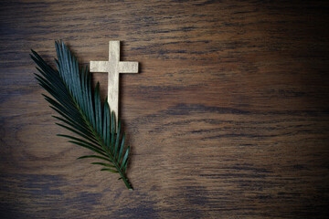 Palm sunday background. Cross and palm on wooden background.