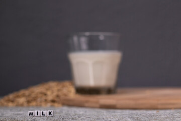pile of raw oatmeal near a glass of milk near word milk written with little white cubes. healthy...