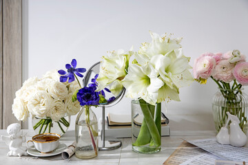 White roses, pink ranunculus, blue anemones, yellowish buttercups, lilies in round vases on the table for a special occasion as a kitchen decoration.