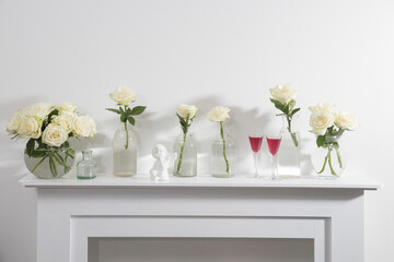 Bouquet of white roses in a glass figured vase on a white fireplace console.