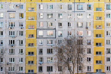 The facade of a nine-storey block house with yellow stripes. Moscow
