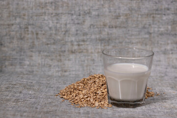 pile of raw oatmeal near a glass of milk. healthy breakfast. vegan oat milk.