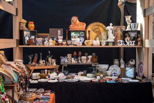 Spitalfields Antique Market. Porcelain figurines, vases, earthenware cup, plates, photo frames, bone beads, dog figures for sale at the flea market.