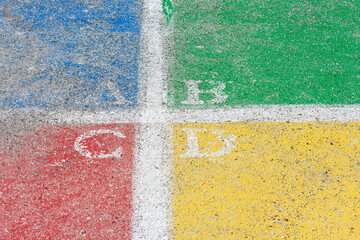 Fototapeta na wymiar Close up of a faded Four Square court painted in bright colors with A B C D painted in each quarter