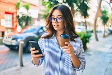 Young hispanic businesswoman with serious expression using smartphone at the city.