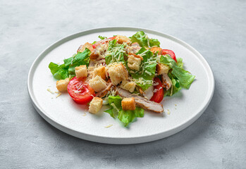Caesar salad on a flat plate on a gray background. Minimalistic culinary background.