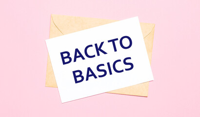 On a light pink background - a craft envelope. It has a white sheet of paper that says BACK TO BASICS.