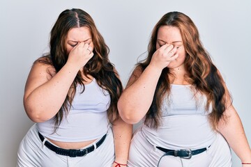 Fototapeta na wymiar Plus size caucasian sisters woman wearing casual white clothes tired rubbing nose and eyes feeling fatigue and headache. stress and frustration concept.