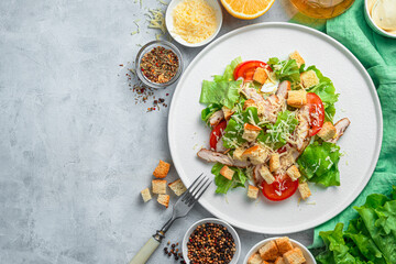 Salad with vegetables and chicken breast on a gray background. Traditional Caesar salad.