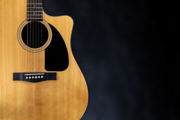 sound board of classic yellow acoustic guitar with black pickguard and strings near isolated black...