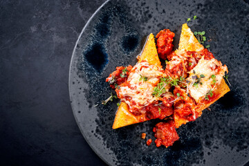 Modern Style traditionelle italienische Polenta alla Sarda con Salsiccia mit Rohwurst serviert als Draufsicht auf einem Nordic Design Teller mit Textfreiraum links 