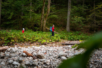 Obraz premium Two backpackers (a woman with a little son) are walking along a creek in a canyon of the Slovak Paradise National Park, Slovakia.
