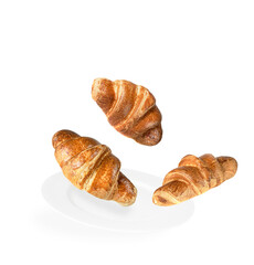 Levitation of three croissants on a white plate and white background.