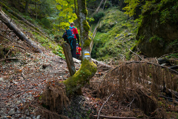 Fototapeta premium Two backpackers (a woman with a little son) are walking along a creek in a canyon of the Slovak Paradise National Park, Slovakia.