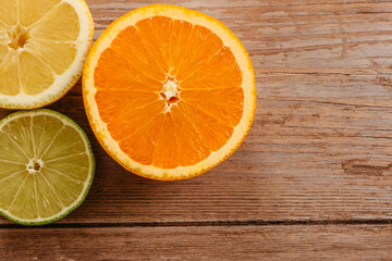 Oranges,limes and lemons slides on wooden table view from above.Beautiful background with fresh fruit half cut.Healthy eating vitamin C.Summer tropical fruits food concept flat lay.Ripe organic citrus