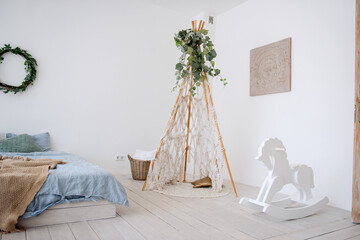 Stylish, trendy interior in Scandinavian style. In white loft room, there is wigwan macrame with...