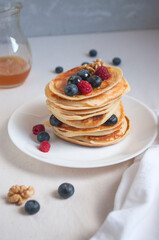 Freshly cooked delicious pancakes with honey, walnut, raspberries and blueberries for breakfast.